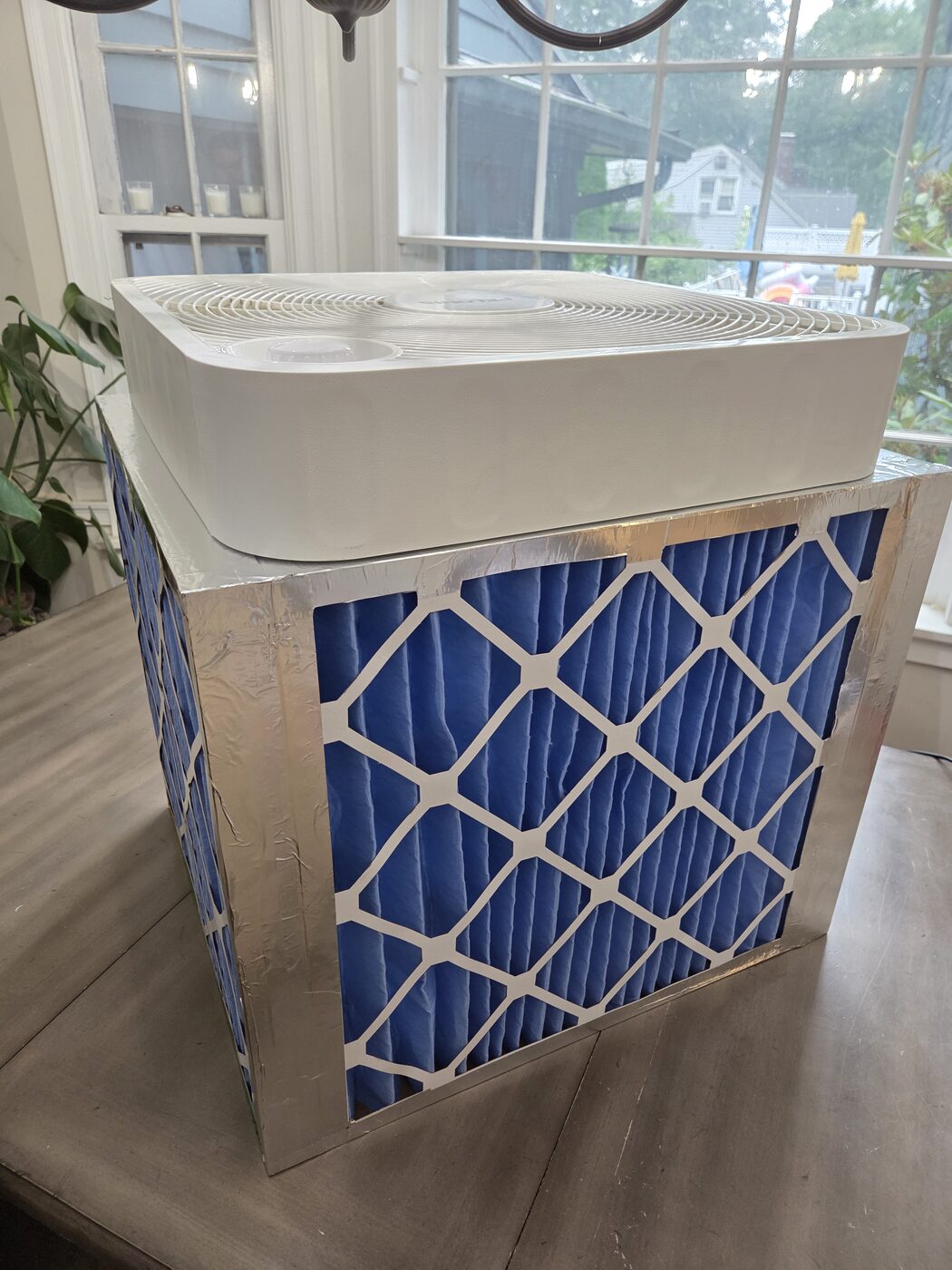 The box fan sitting on top of the filter cube, blowing upward and out.